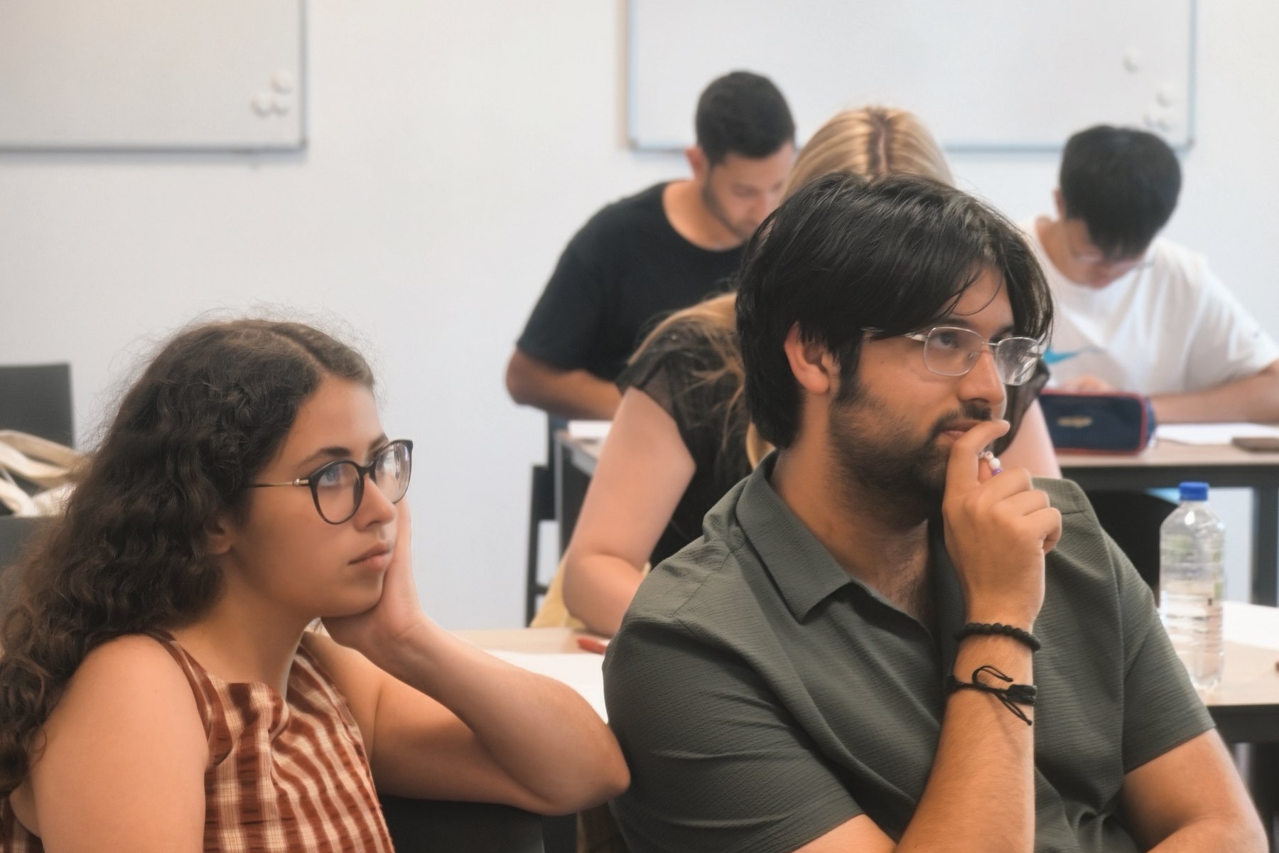 People working at desks in a teaching room during a session